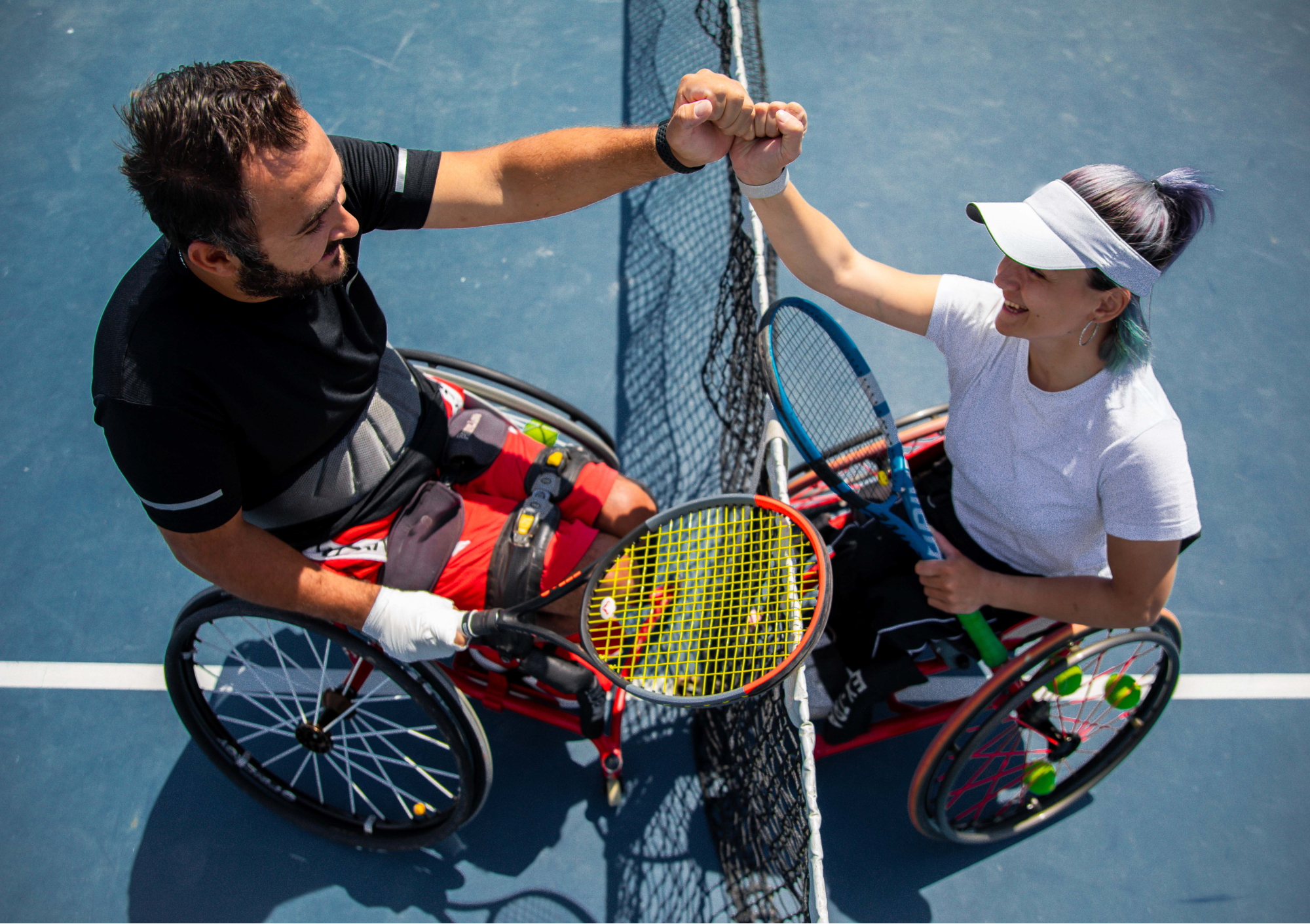 twee mensen in een rolstoel op de tennisbaan