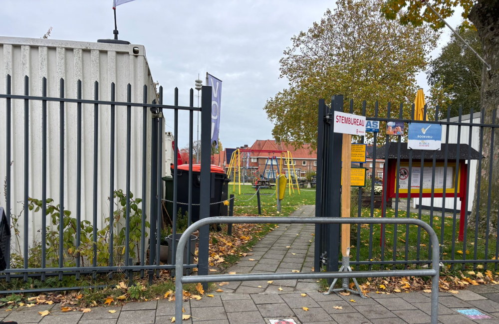 Ingang van een stembureau met hek en dranghek voor het pad; de toegang oogt smal en minder goed toegankelijk.