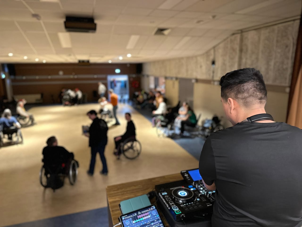 Een dj kijkt uit over de dansvloer tijdens de rolstoeldansmiddag