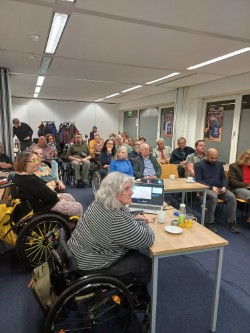 Bezoekers, waaronder rolstoelgebruikers, tijdens een bijeenkomst